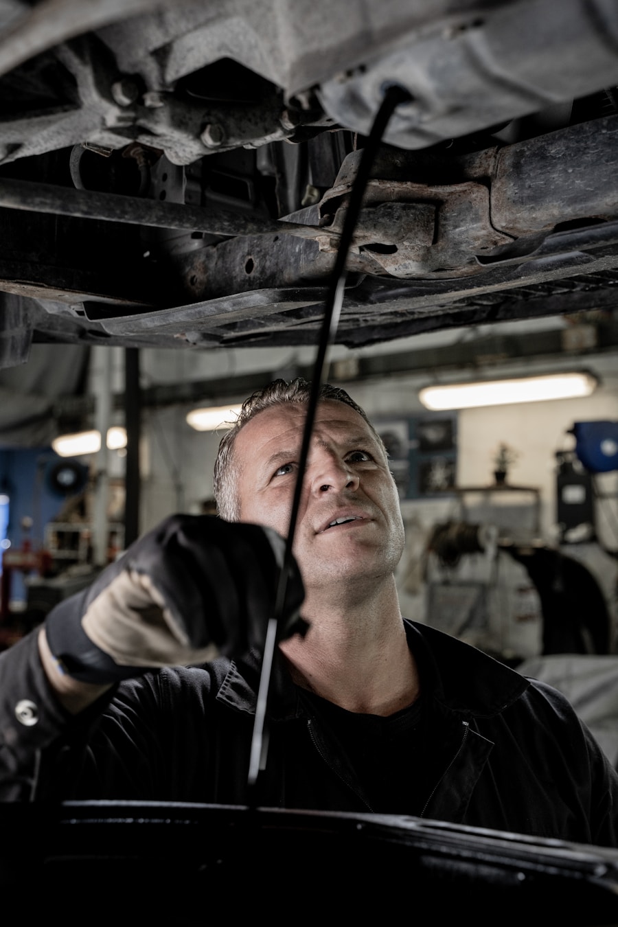 Technician draining oil beneath a lifted vehicle